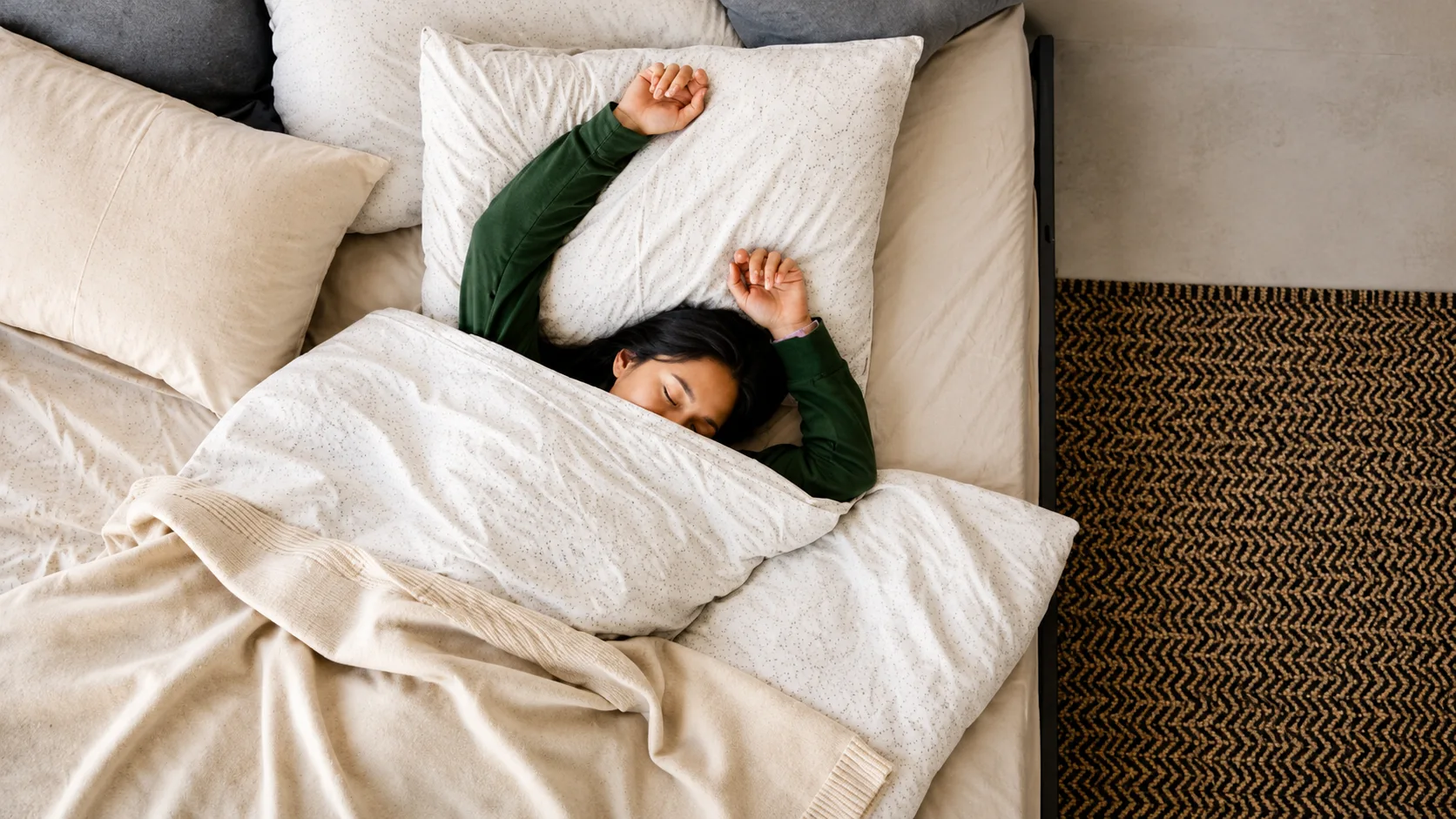 Person sleeping peacefully in bed with soft, layered linens 