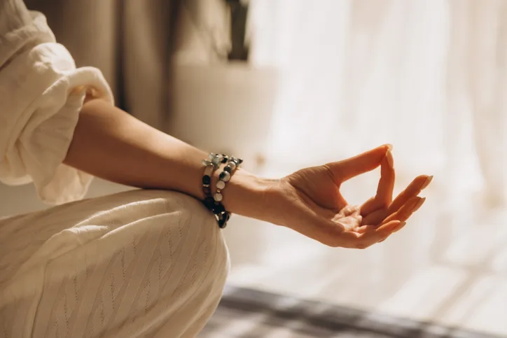 Hand in Gyan Mudra meditation gesture with beaded bracelet