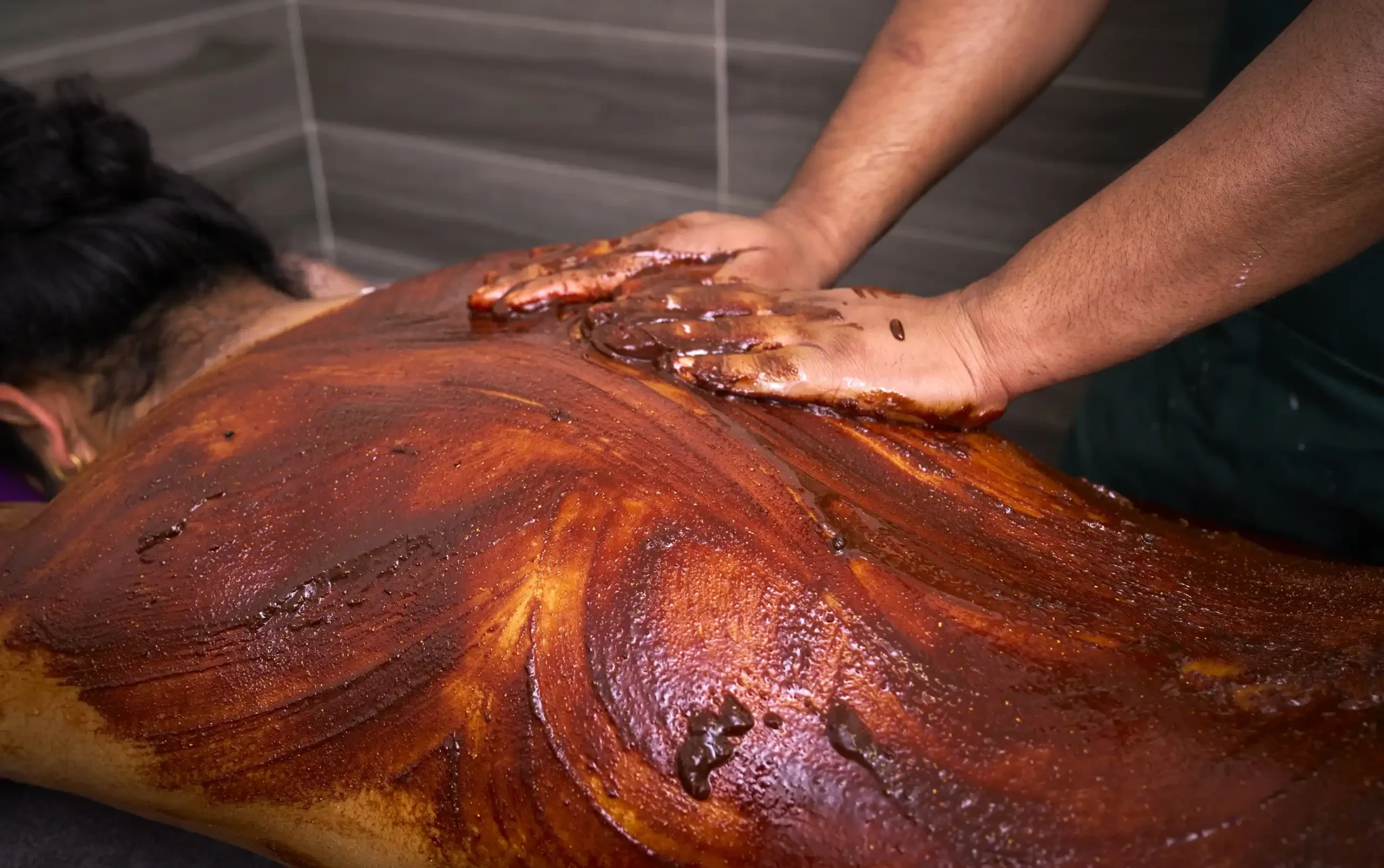 Ayurvedic oil massage on back with herbal paste application